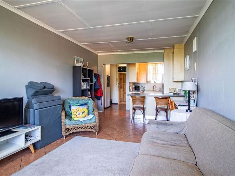 Open plan living area featuring tiled flooring and a functional kitchen with breakfast bar, providing a versatile space for daily living.