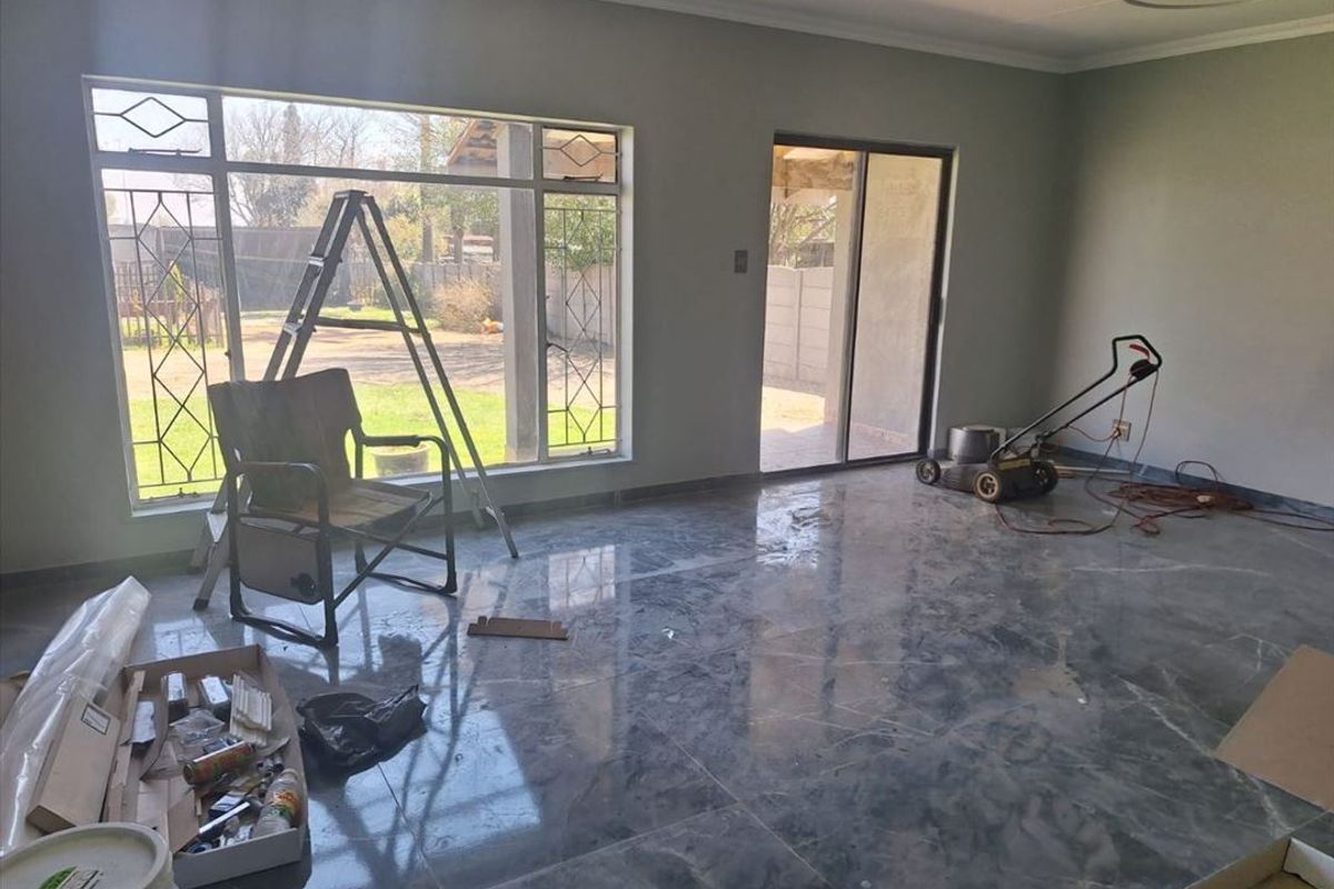 Spacious living area featuring large format polished floor tiles, ample natural light from large windows, and direct access to the outdoor patio area.