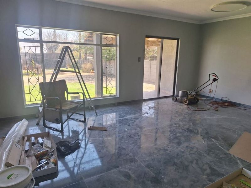 Spacious living area featuring large format polished floor tiles, ample natural light from large windows, and direct access to the outdoor patio area.