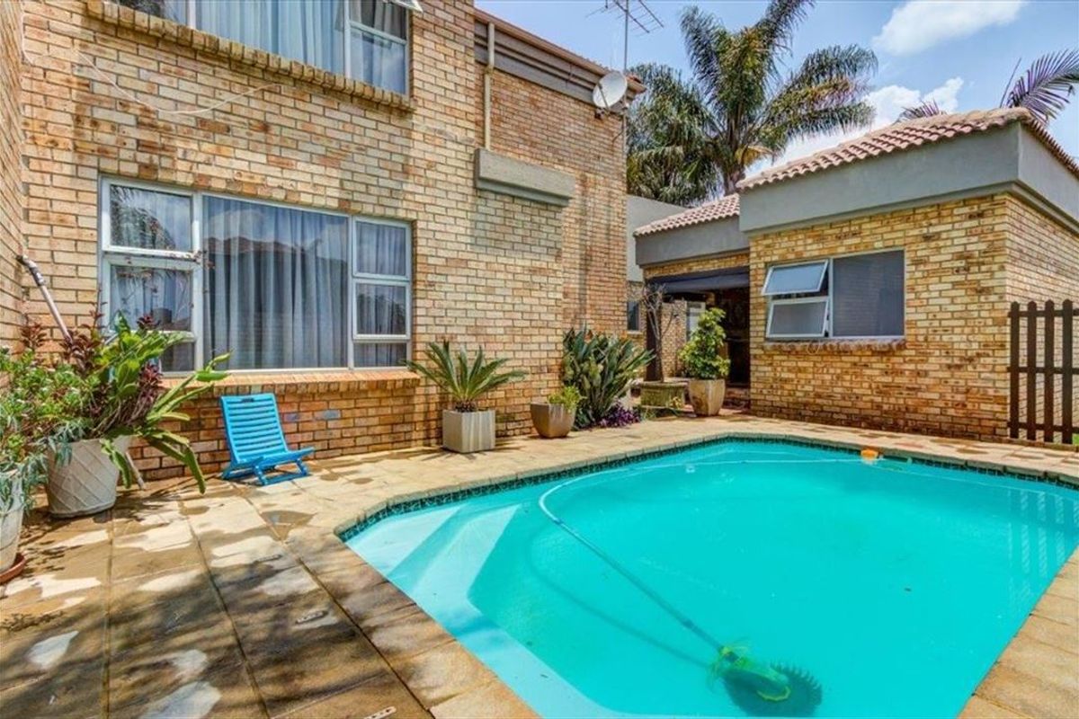 Outdoor pool area featuring a paved patio, brick exterior walls, and aluminum window frames, providing a functional space for outdoor relaxation.