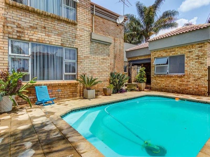 Outdoor pool area featuring a paved patio, brick exterior walls, and aluminum window frames, providing a functional space for outdoor relaxation.