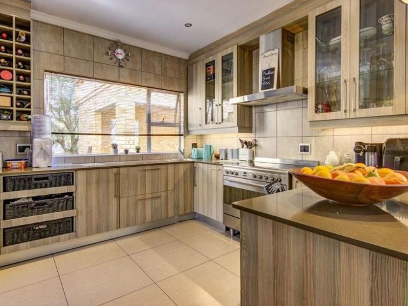 A well-appointed kitchen featuring wood-grain cabinetry, stainless steel appliances, tiled backsplash, and integrated wine storage with ample counter space.