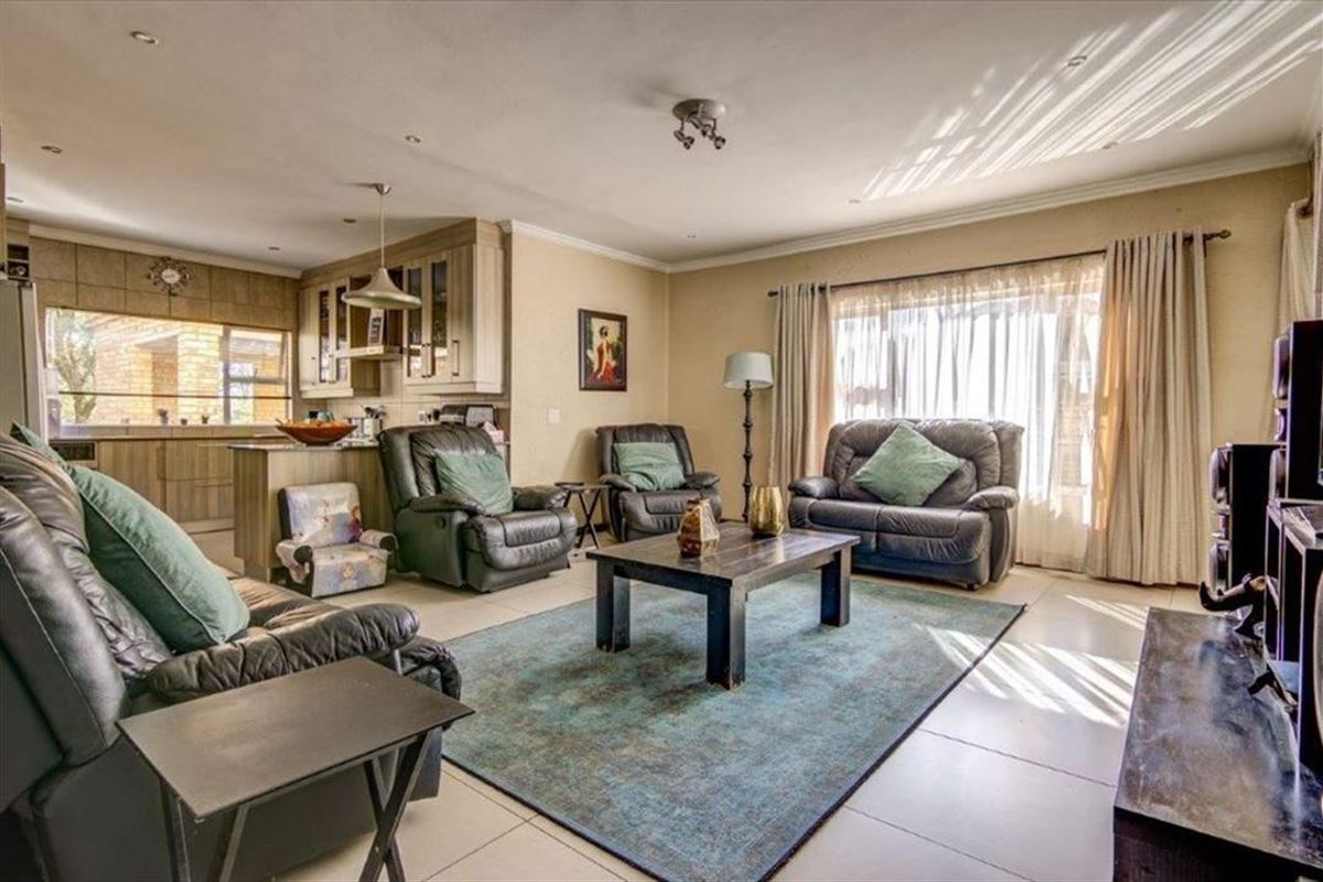 Spacious open-plan living area featuring tiled floors, integrated kitchen cabinetry with an island, and large sliding doors providing natural light.