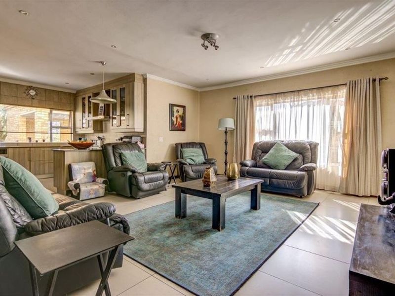 Spacious open-plan living area featuring tiled floors, integrated kitchen cabinetry with an island, and large sliding doors providing natural light.