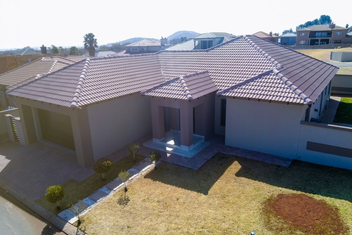 Aerial view of a modern townhouse featuring a tiled roof, paved driveway, integrated garage, and a covered entrance area.