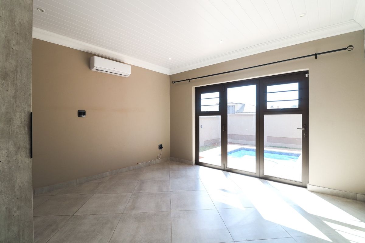 Bright and spacious living area featuring tiled floors, air conditioning, and large aluminium sliding doors providing direct access to the pool area.