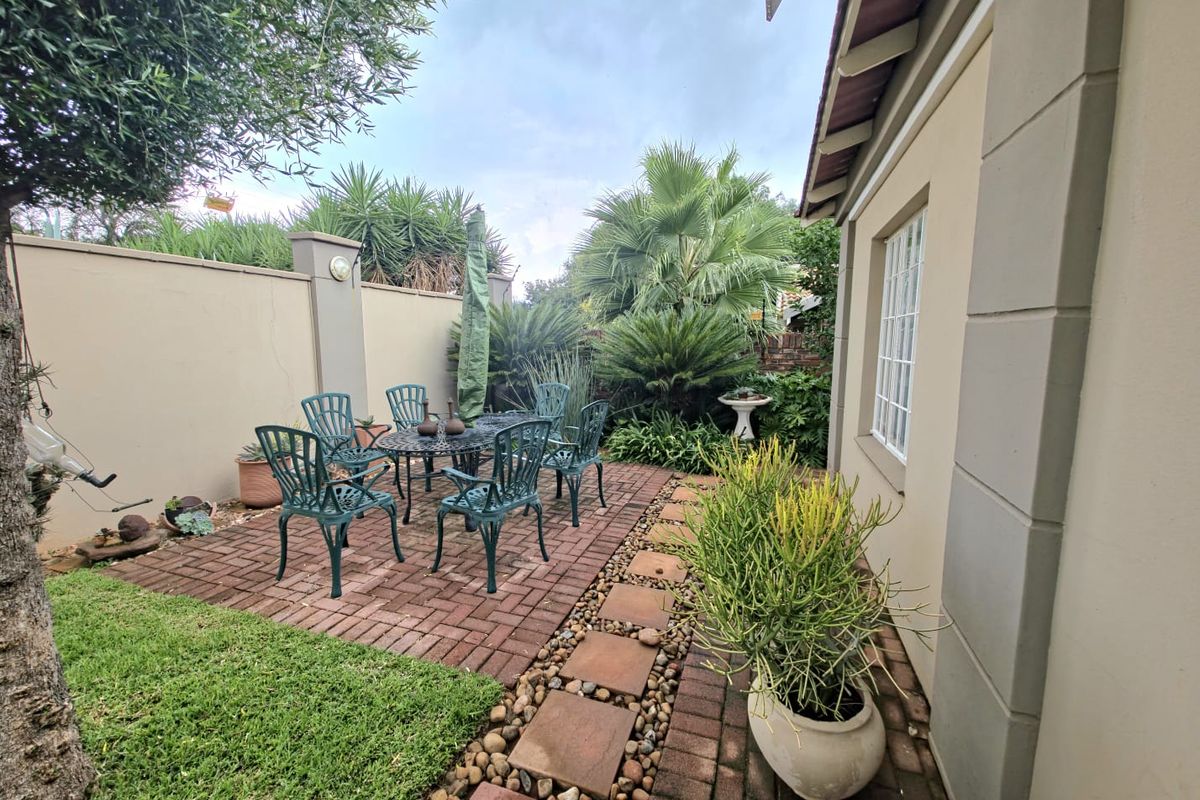 A private rear garden featuring a brick-paved patio area, established landscaping, and a secure boundary wall, ideal for outdoor relaxation.