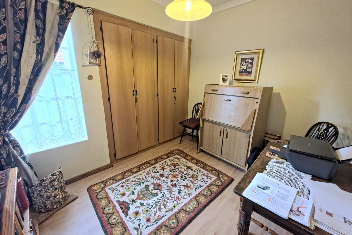 A bedroom featuring light-toned laminate flooring and a large, built-in wooden wardrobe providing ample storage space.