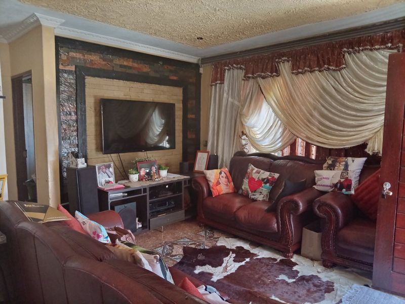 A living room featuring a stone accent wall, textured ceiling, and tiled flooring, offering a traditional layout with potential for modern updates.