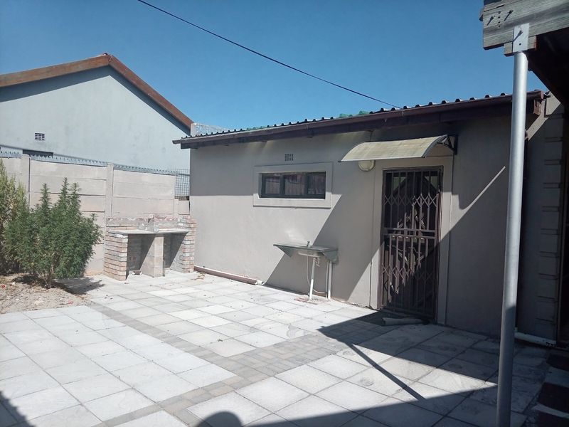 Outdoor patio area featuring a built-in brick braai, external sink, and paved flooring, providing a functional space for outdoor entertaining.