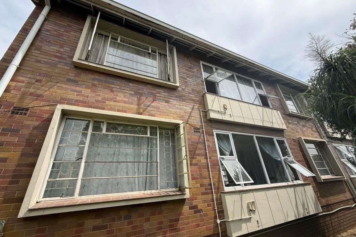 Exterior view of a multi-story apartment building featuring traditional brick facade and original steel-framed casement windows.