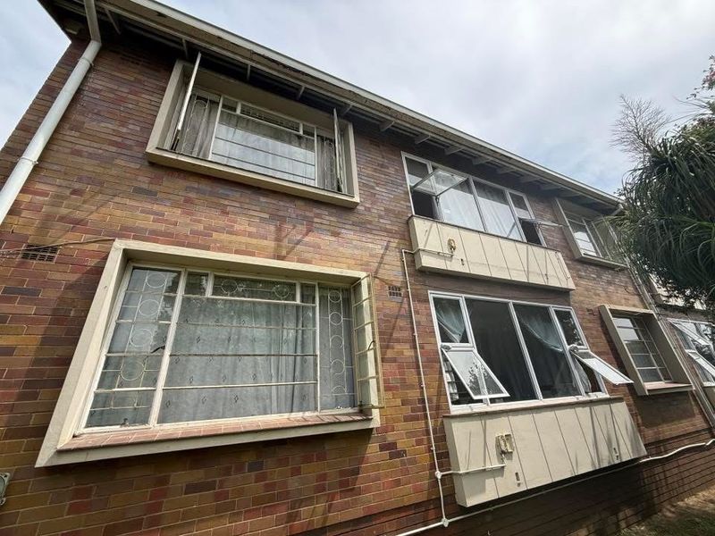 Exterior view of a multi-story apartment building featuring traditional brick facade and original steel-framed casement windows.