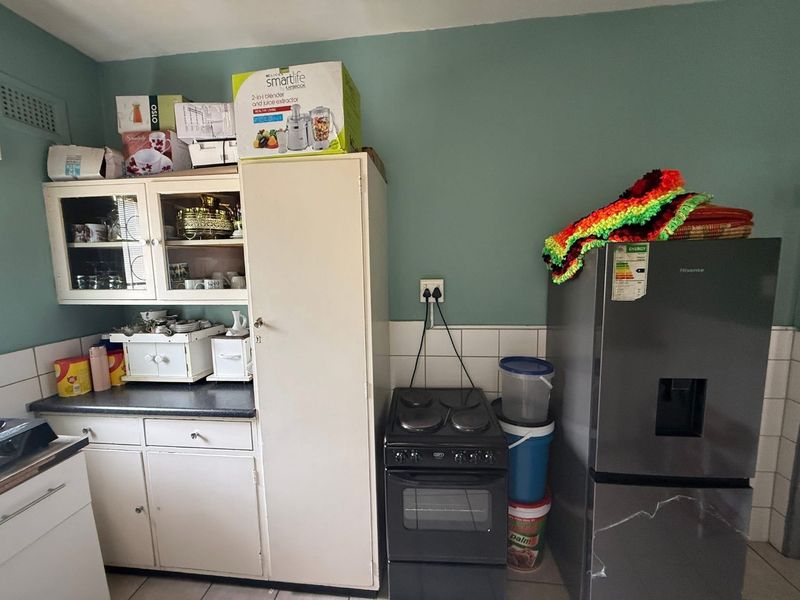 A functional kitchen area featuring built-in cabinetry, a tiled backsplash, and an electric stove, offering potential for modernization and improved storage layout.