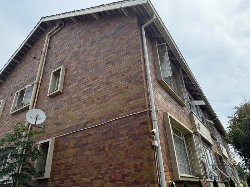 Side elevation of a multi-story brick apartment building featuring casement windows, external downpipes, and guttering.