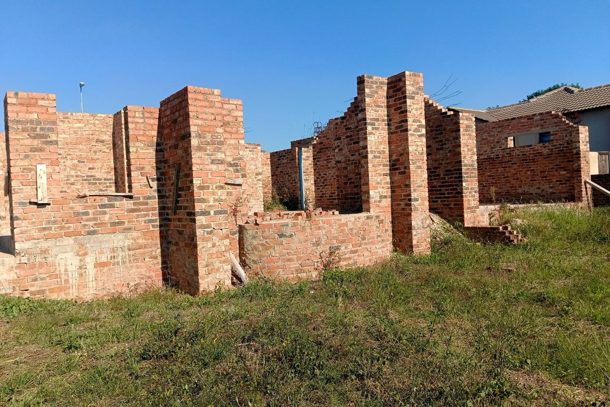 An unfinished residential construction site showing exposed brick walls and structural masonry in the early stages of development.