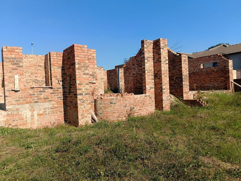 An unfinished residential construction site showing exposed brick walls and structural masonry in the early stages of development.