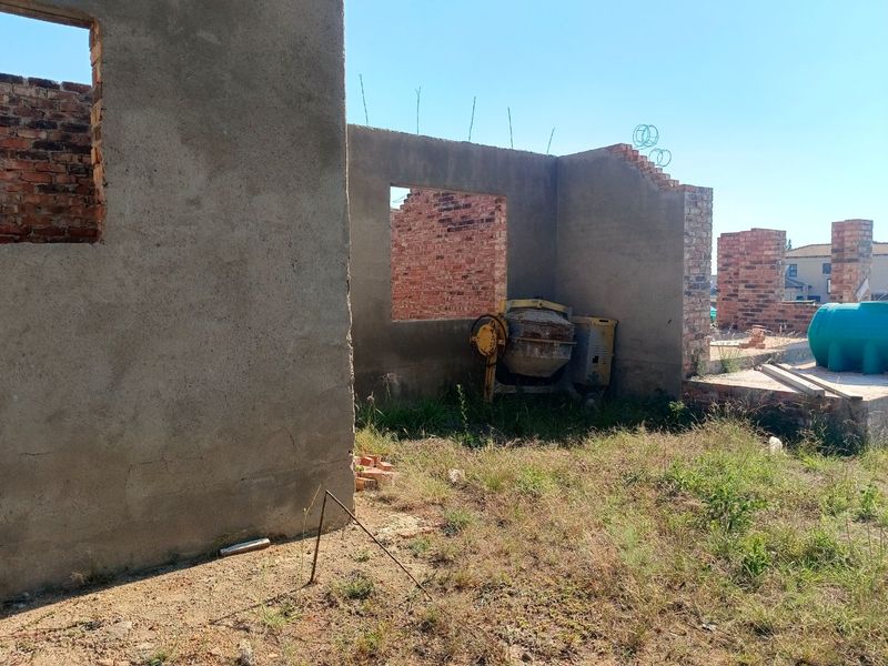 A view of a property under construction, featuring exposed brick walls and cement plastering in an early development stage.
