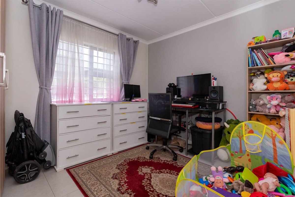 A functional bedroom featuring tiled flooring, a window with curtain tracks, and coved ceiling detailing.