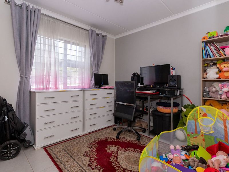 A functional bedroom featuring tiled flooring, a window with curtain tracks, and coved ceiling detailing.