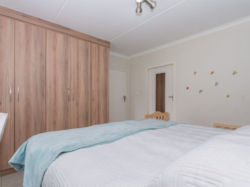 A well-maintained bedroom featuring ample built-in wooden cupboards, neutral wall finishes, and a clean, functional layout.