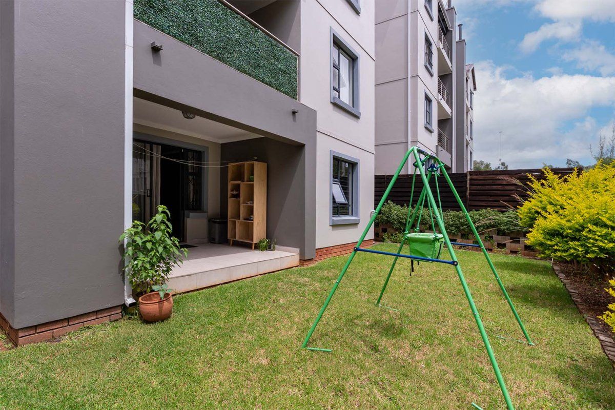 A ground floor apartment featuring a private tiled patio area leading out to a small, well-maintained garden space with boundary fencing.