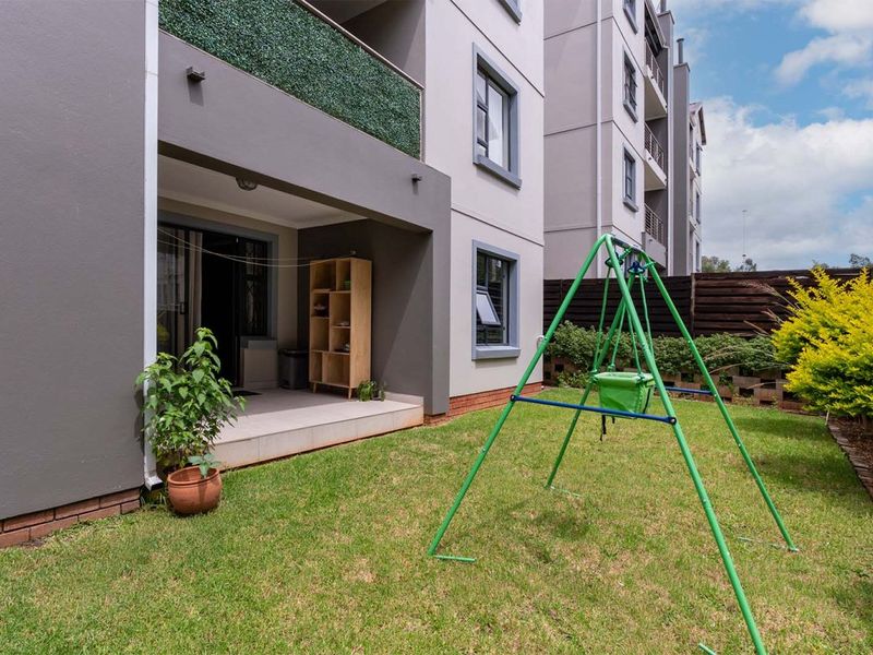 A ground floor apartment featuring a private tiled patio area leading out to a small, well-maintained garden space with boundary fencing.