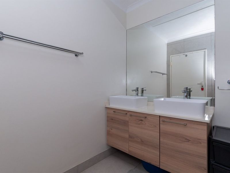 Modern bathroom featuring a double vanity with vessel sinks, wood-finish cabinetry, and a large wall-mounted mirror.