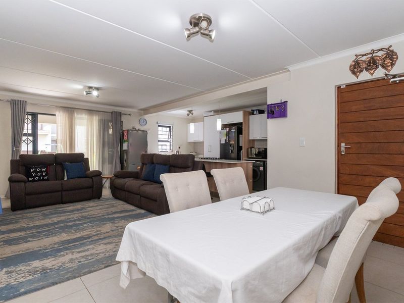 Spacious open-plan living and dining area featuring tiled floors, modern kitchen cabinetry, and direct access to an outdoor patio through sliding glass doors.