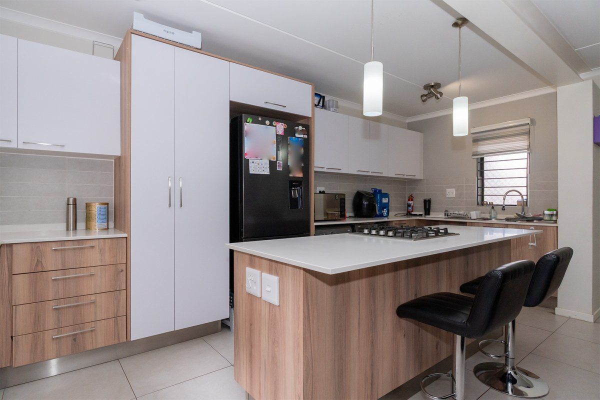 Modern kitchen featuring a central island with a gas hob, stone countertops, ample built-in cabinetry, and tiled flooring.
