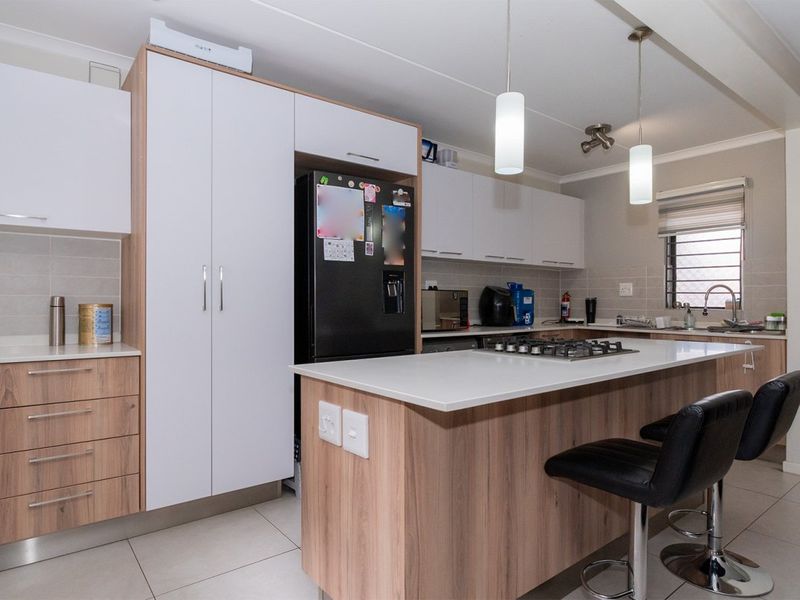 Modern kitchen featuring a central island with a gas hob, stone countertops, ample built-in cabinetry, and tiled flooring.