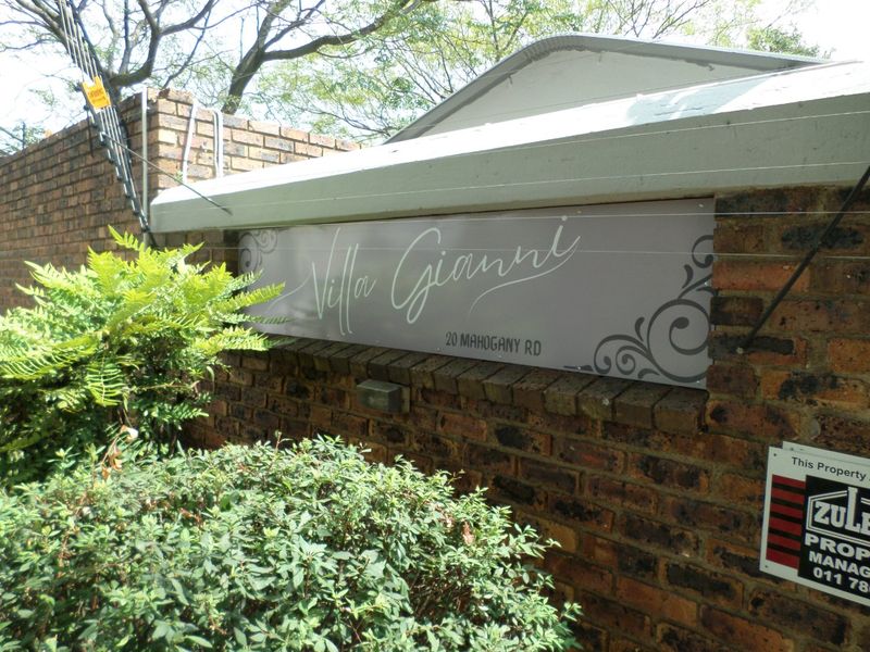 Exterior view of the property entrance featuring a brick boundary wall with electric fencing and the Villa Gianni signage.
