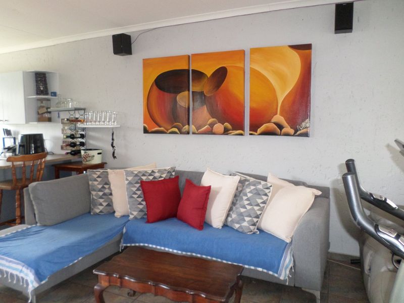 A living room area featuring tiled flooring and wall-mounted audio speakers, providing a functional space for relaxation.