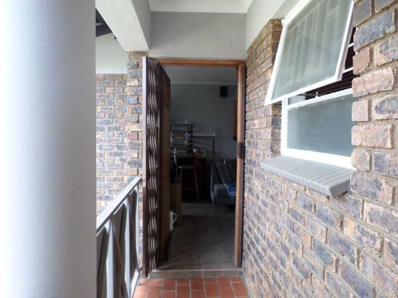 Entrance area featuring a brick facade, security gate, and a tiled balcony, providing access to the interior living space.
