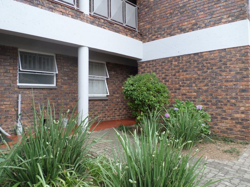 A ground floor patio area featuring face brick walls, a concrete support column, and paved flooring, overlooking a small garden space.