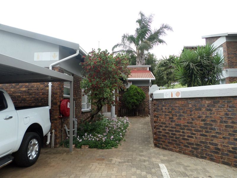 Exterior view of the apartment complex featuring a brick facade, paved driveway, and a covered carport area.