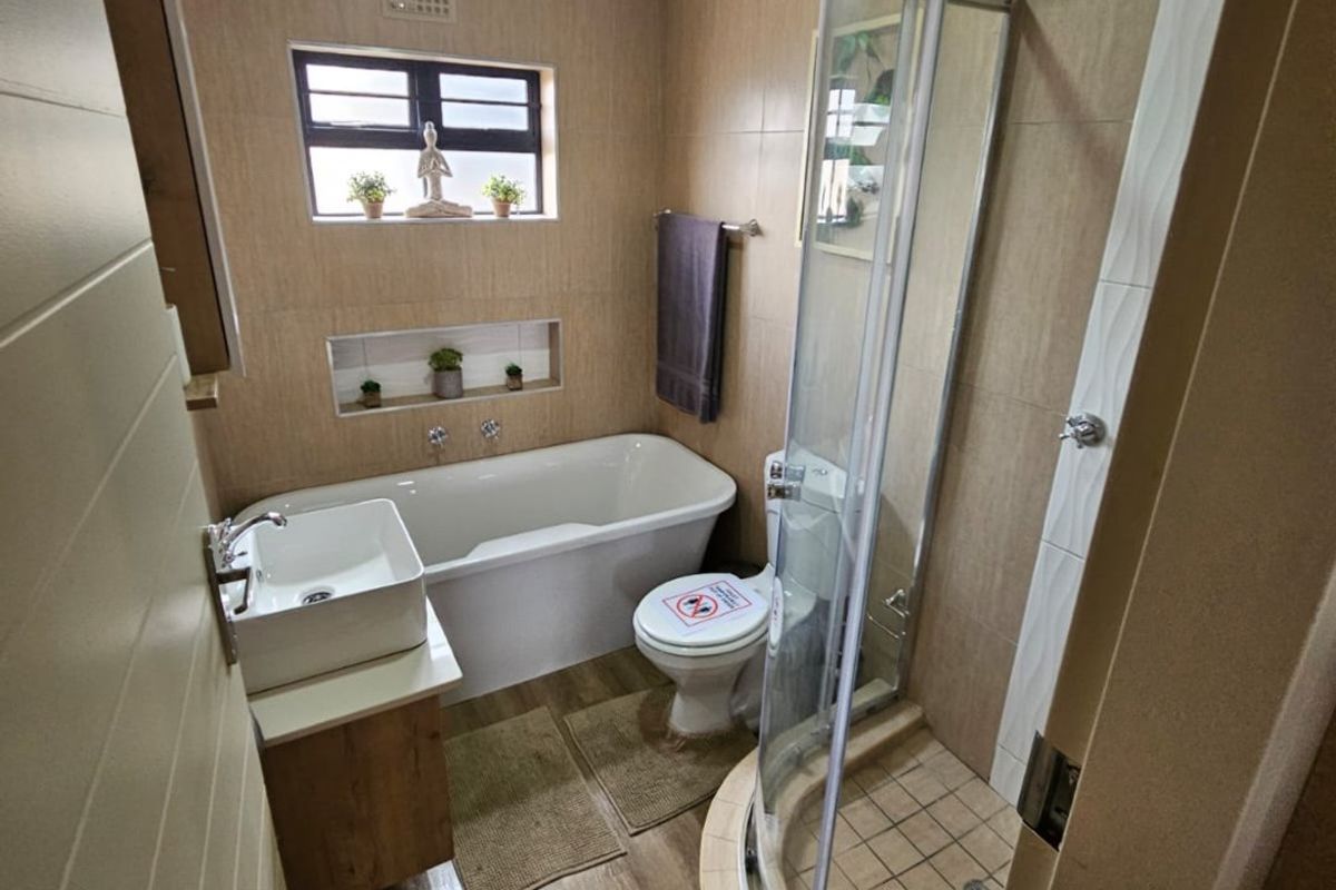 Modern bathroom featuring a bathtub, separate curved shower enclosure, vanity basin, and neutral tiled finishes throughout.