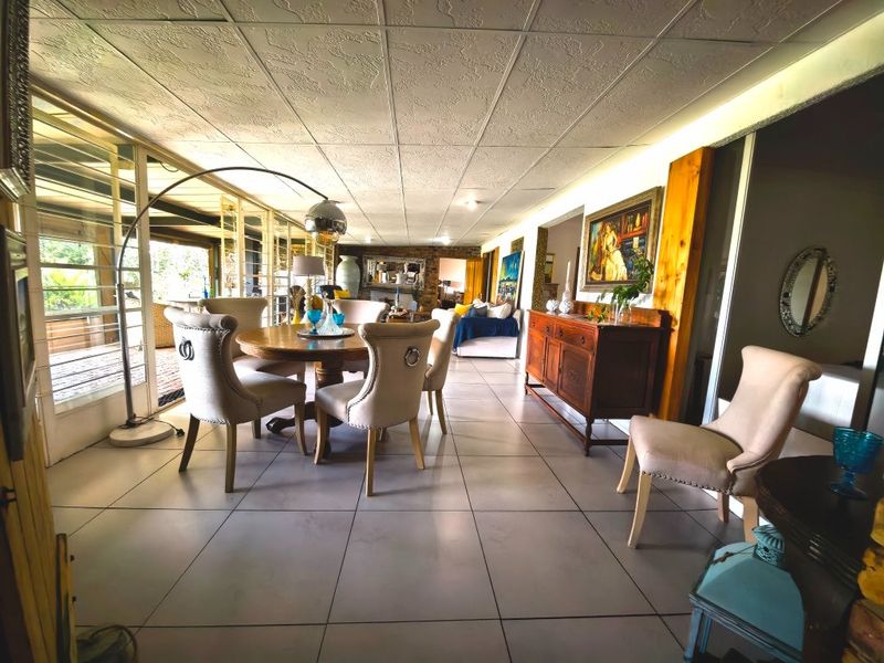Spacious open-plan living and dining area featuring large sliding glass doors, tiled flooring, and a distinctive stone feature wall.
