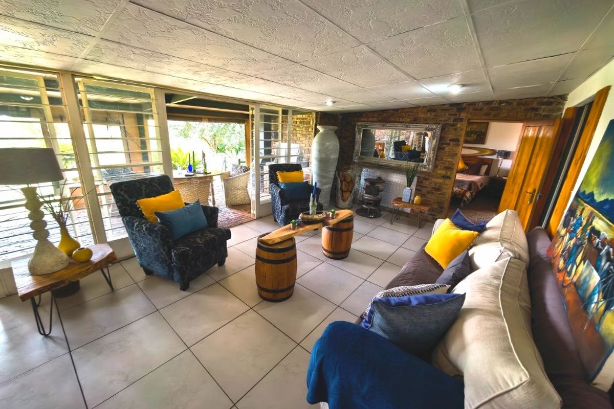 Spacious living room featuring tiled flooring, an exposed brick wall, and large sliding glass doors providing access to the outdoor patio area.