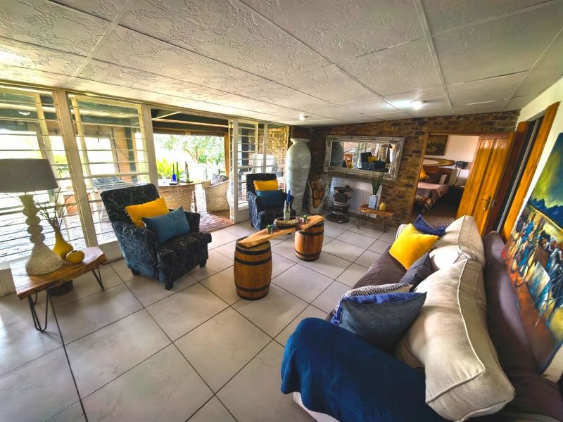 Spacious living room featuring tiled flooring, an exposed brick wall, and large sliding glass doors providing access to the outdoor patio area.
