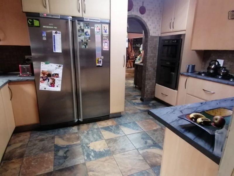 A functional kitchen featuring built-in cabinetry, a double oven, gas hob, and durable tiled flooring with an arched transition to the adjacent living space.