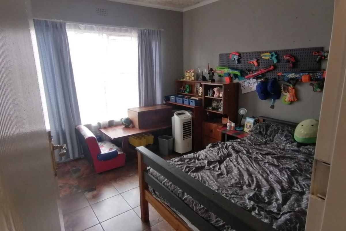 A functional bedroom featuring tiled flooring and large windows with curtain rails, offering a blank canvas for potential interior updates.
