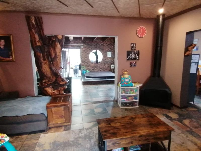 Living room featuring a freestanding fireplace, tiled flooring, and a unique decorative timber pillar, leading into an adjacent space with exposed brick walls.