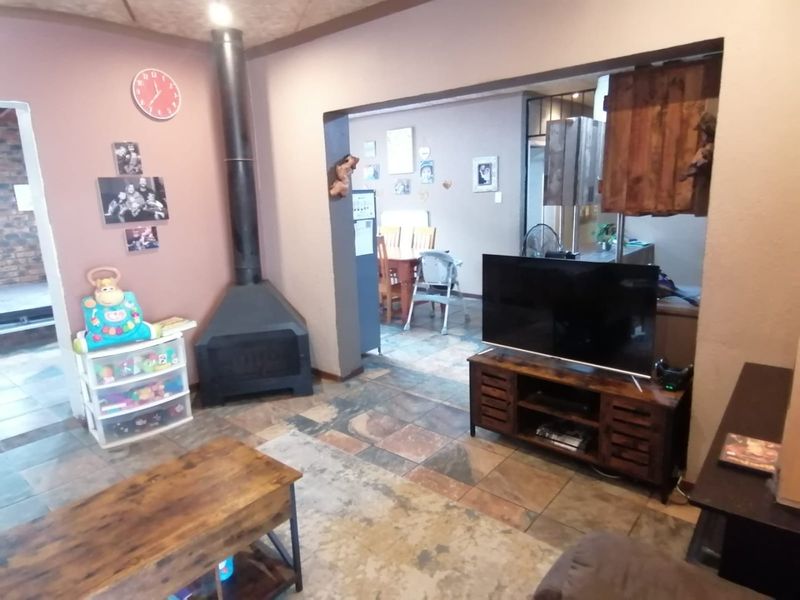 Open plan living area featuring tiled flooring and a prominent freestanding fireplace, connecting to the adjacent dining space.