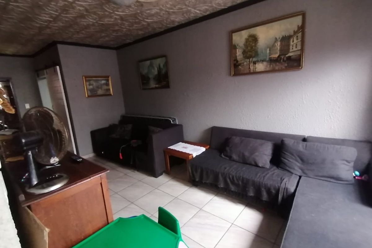 A living room featuring tiled flooring and a textured ceiling, providing a functional space for relaxation.