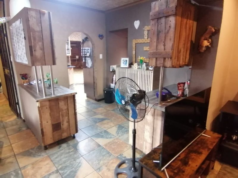 Open plan living area featuring rustic wooden cabinetry, tiled flooring, and an arched doorway leading to an adjacent room.