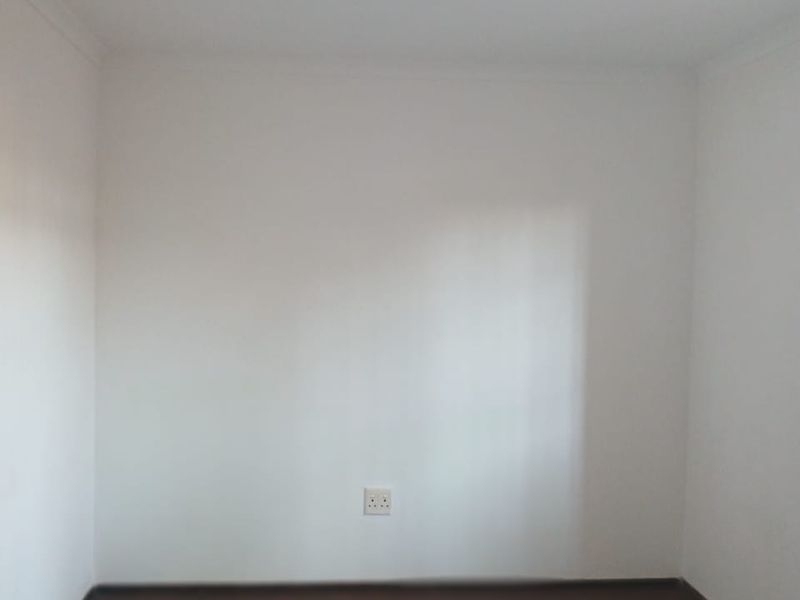 A vacant bedroom featuring neutral walls, carpet flooring, and a central ceiling light fixture, providing a blank canvas for personalization.