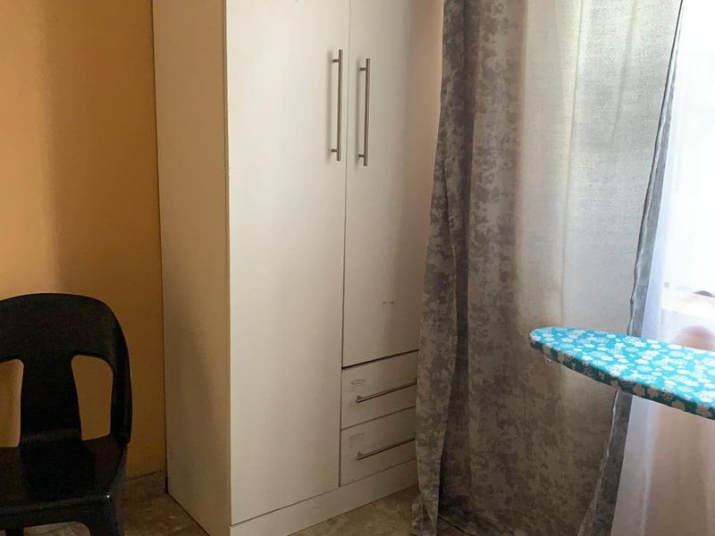 A bedroom featuring tiled flooring and a white built-in wardrobe with integrated drawers.