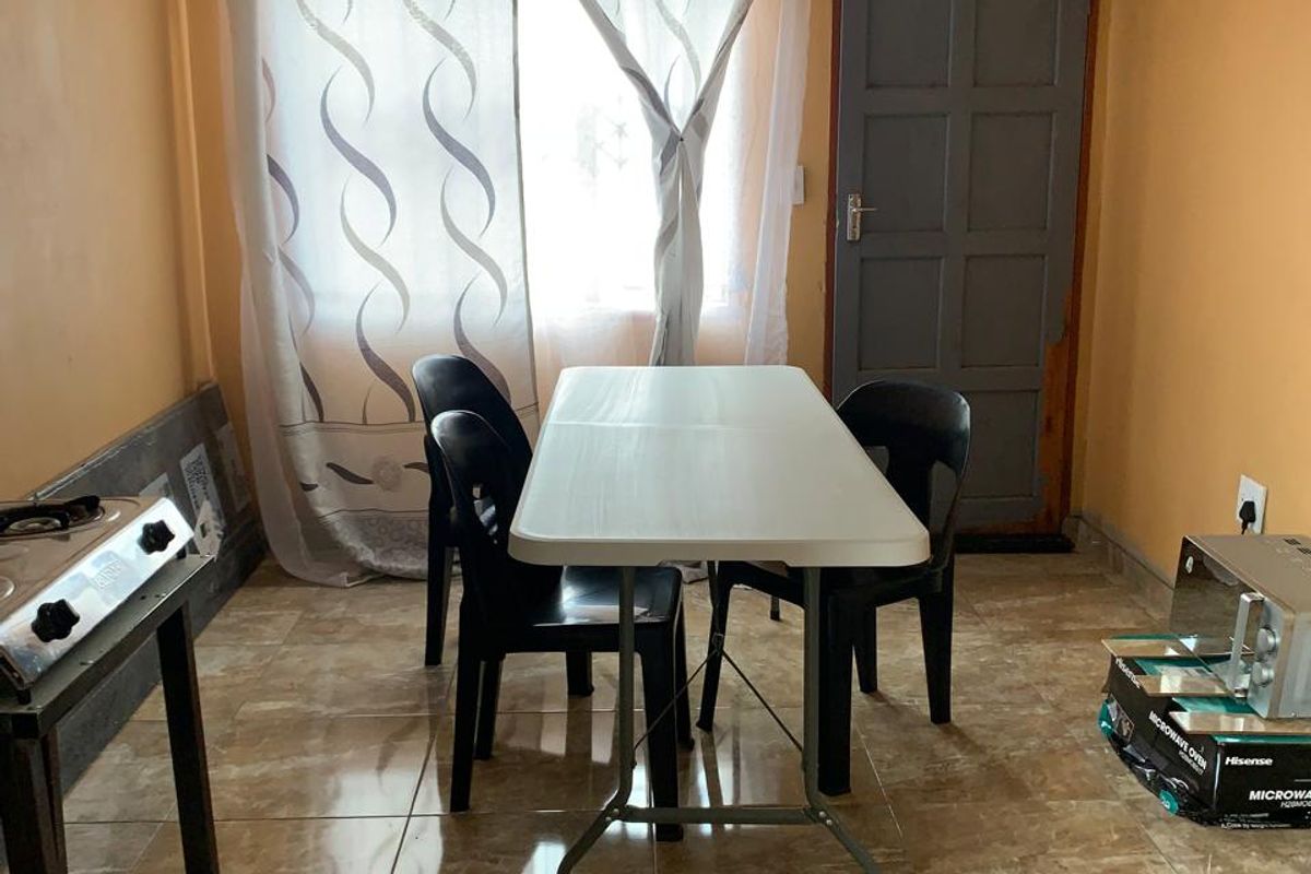 A simple dining area featuring tiled flooring and a panel door, offering a functional space that could benefit from cosmetic updates.