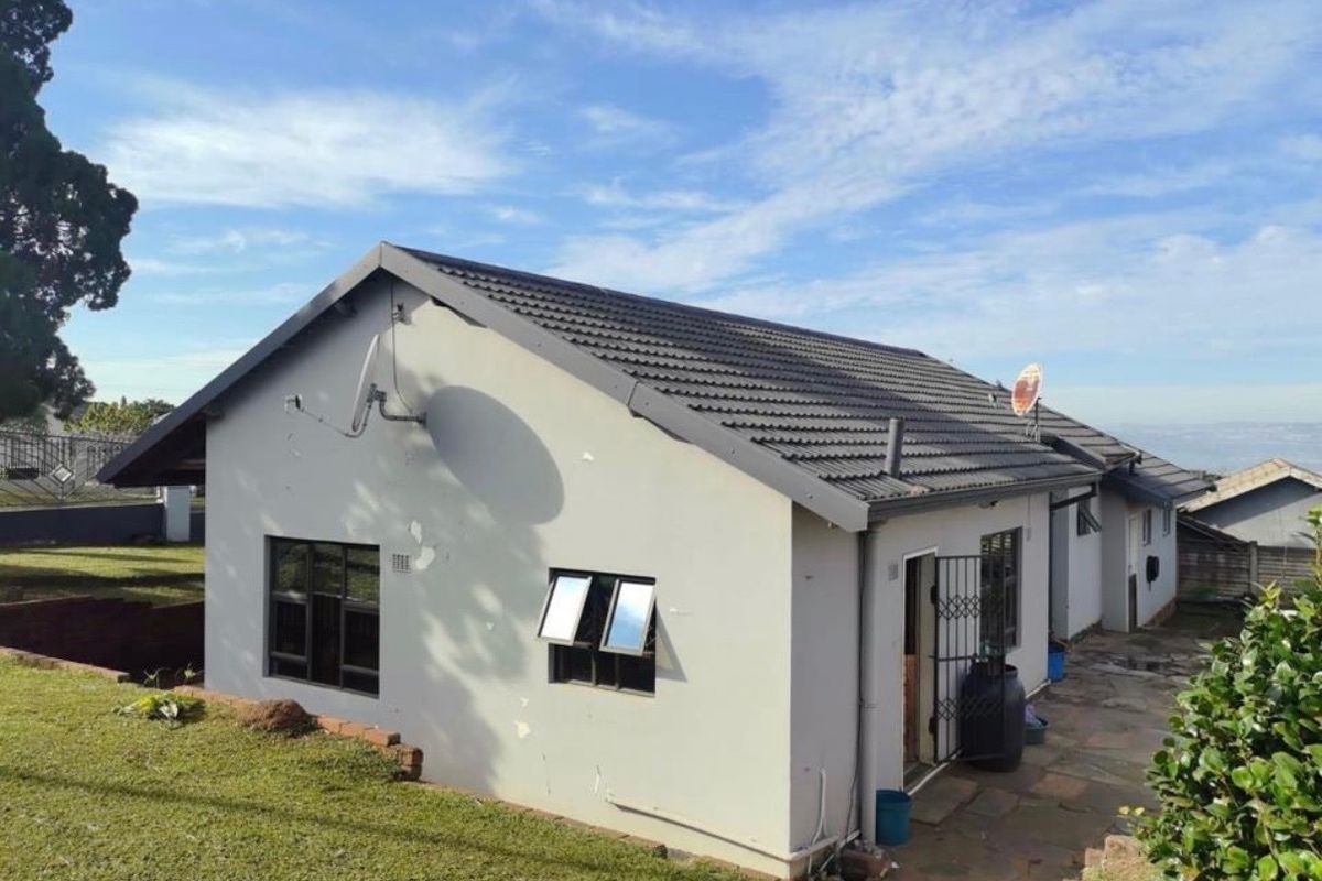 Rear view of the house featuring a tiled roof, paved patio area, and security gate access.