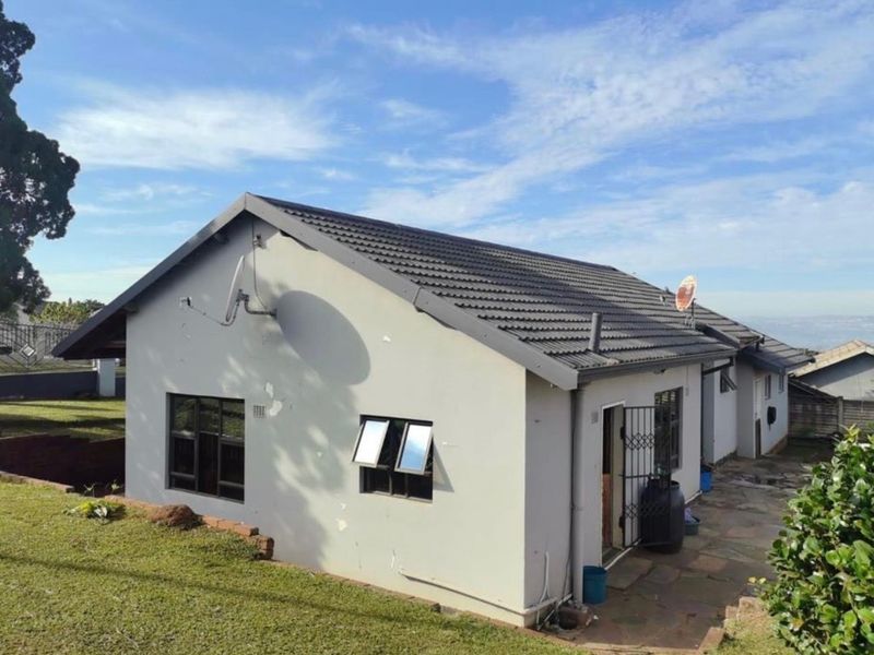 Rear view of the house featuring a tiled roof, paved patio area, and security gate access.